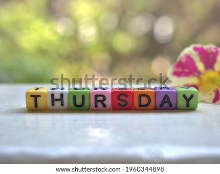 Thursday alphabet letters ,colorful word on white table with pink petunia flower and bokeh blurred background ,happy morning for creative card design ,sweet color ,fresh morning day Royalty-Free Stock Photo #1960344898
