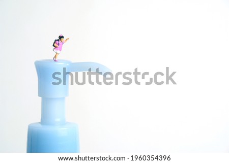 Reopen school class on corona virus pandemic. Children or kids, walk above disinfectant hand sanitizer bottle. Miniature tiny people toys photography. isolated on white background.