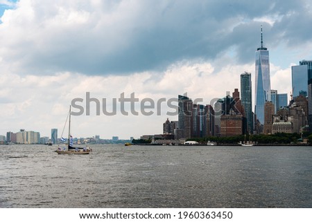 Skyline of Downtown of Manhattan from Goversnors Island a cloudy day of summer. Sailing Ship navigating on Hudson Reiver agasint Cityscape. Travel to USA