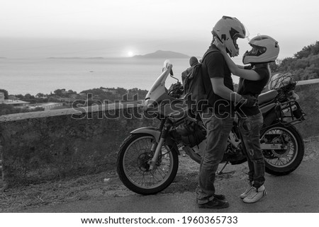 Beautiful couple in love and motorcycle on the street, outdoor portrait, travel together, Sunset over the Capri island, sea and mountains. Journey vacation. Black and white. Copyspace