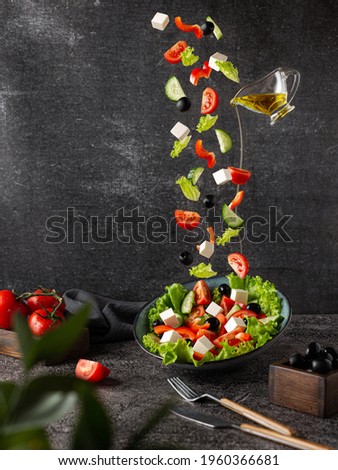 Flying vegetables are the ingredients of a Greek salad. On a dark background with props