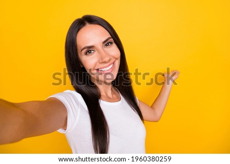 Photo portrait of brunette influencer taking selfie smiling showing with hand copyspace isolated on bright yellow color background