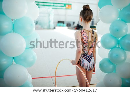 the rhythmic gymnastics girl looks at the performing friends waiting for her turn. sports competitions that require agility and flexibility. training warm-up