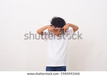 Asian kid with red white headband pointing and present to present an empty space of content.Wow and shocked face of Asian kid. Advertising model concept.