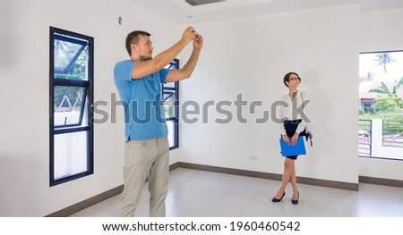 Estate Agent Showing Young man new empty property, client making photos.