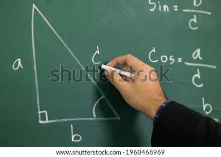 Education background concept. Close up male hand writing mathematical formula on chalkboard.