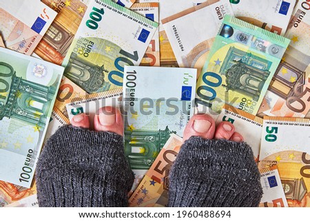 feet in torn holey socks on euro money
