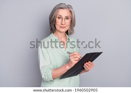 Photo of happy good mood beautiful confident woman in glasses writing in organizer isolated on grey color background
