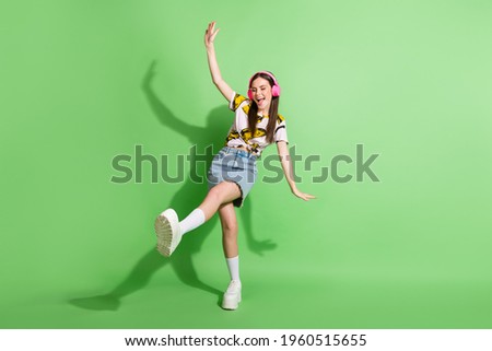 Full length photo of attractive young woman wear headphones dance isolated on green color background