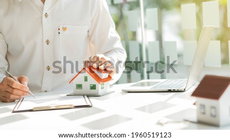 Real estate agents are introducing house forms and contract documents with a laptop on their desk.