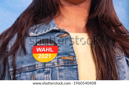 Young woman with brown hair and an election button for the German federal election on their Jeans jacket , with the inscription: "Bundestagswahl 2021" (Federal Election 2021). Royalty-Free Stock Photo #1960540408