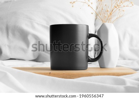 Black mug mockup and a gypsophila on the bed.