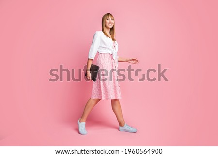 Full length body size photo of woman walking on meeting in printed dress shirt keeping laptop isolated on pastel pink color background