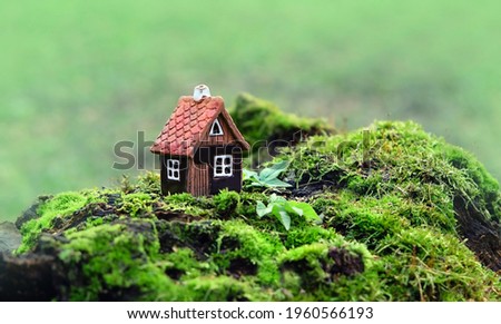Toy house on moss, green natural abstract forest background. Symbol of family, Mortgage, Real estate concept. Eco Friendly Home. Fairy tale house in green woodland, pixie and elf home