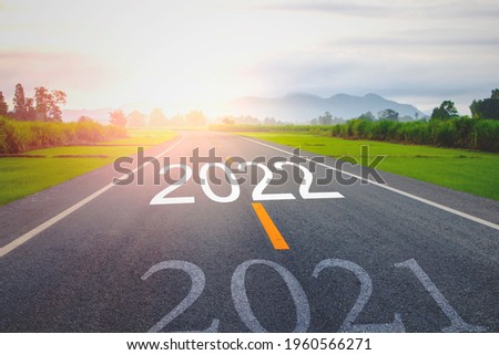 Concept new year With The word 2021 to 2022 Written on The asphalt  road in country road Decorate orange light for beauty With With views of rice fields on both sides Concept for the new year of 2022