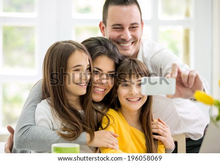 happy family with little girls making self portrait with smart phone