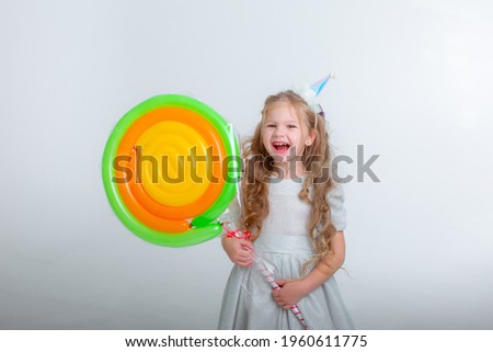 little girl in a birthday cap with a lollipop on a white background studio