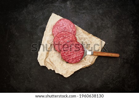 Uncooked Ground Beef Patties for Grilling. Raw Minced Steak Burgers from Beef and Pork Meat on Black Background. BBQ Grill Tools with Raw Beef Hamburger Patties. Raw Burger Cutlets.