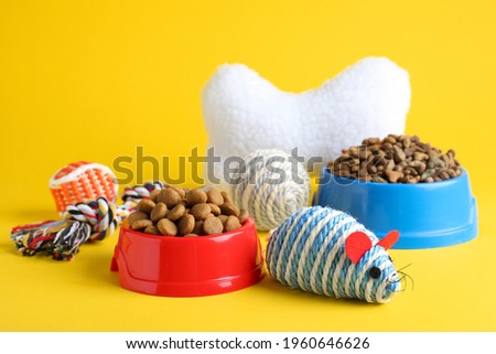 Feeding bowls and toys for pet on yellow background Royalty-Free Stock Photo #1960646626