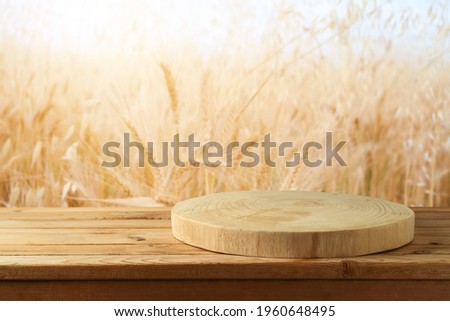 Empty wooden log on rustic table over wheat field background.  Jewish holiday Shavuot mock up for design and product display. Royalty-Free Stock Photo #1960648495