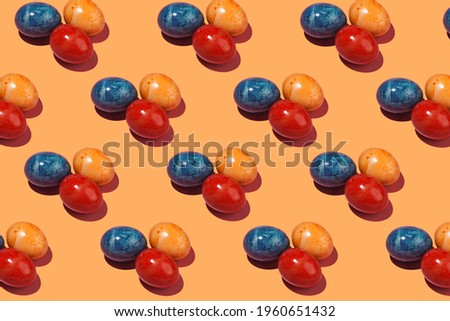 A hard light pattern of three colored easter eggs on an orange background