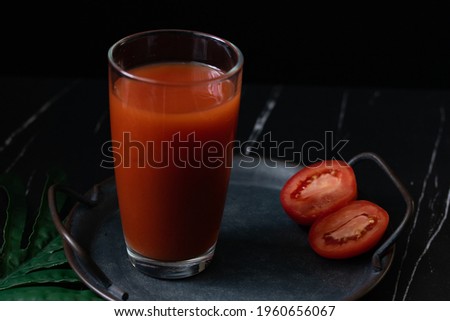 Red cocktail with tomato juice in a clear glass, dark tone picture.