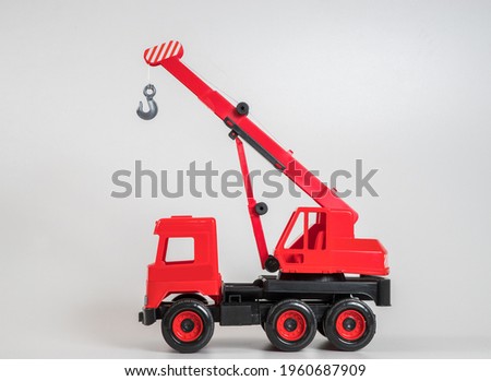 Multi-colored plastic children's toy cars on a white background. Red truck crane.