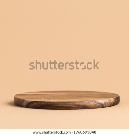 Round wooden podium for food, products or cosmetics against bright brown background.