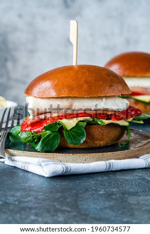 Grilled halibut sandwich in brioche bun with bacon, red romano pepper, courgette and lamb's lettuce