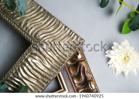 Corners of empty picture frames and flowers on grey canvas backdrop. Samples of photo frame on floral background. Home decor, framing workshop concept.