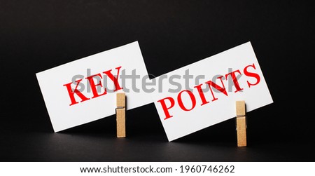 On a black background on wooden clothespins, two white blank cards with the text KEY POINTS