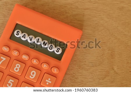 Top view of calculator and alphabet beads with text SAVINGS. Financial concept