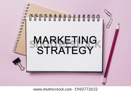 Text Marketing Strategy on a white sticker with office stationery background. Flat lay on business, finance and development concept