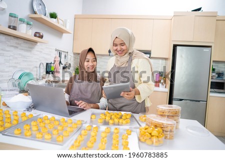 two young small muslim business owner selling homemade nastar cake from home. muslim woman baking pineapple tart together for eid mubarak Royalty-Free Stock Photo #1960783885