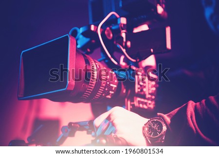 Modern Video Camera with Telephoto Lens and Camera Operator. Digital Motion Picture Equipment.