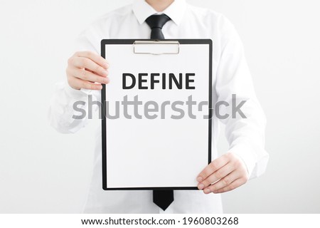 The word DEFINE on white paper in the hands of a businessman on a gray background. Business concept