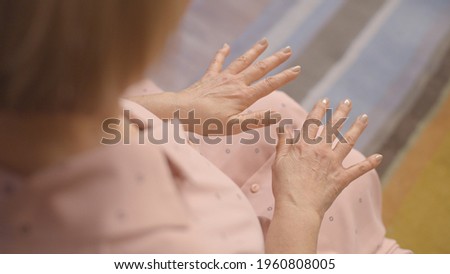 The quake hands of the old woman on her knees. Close-up. Top angle. Old shaking hands concept. Parkinson disease concept.