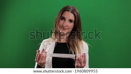 Young woman puts on a medical face mask - studio photography