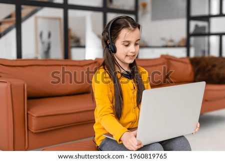 Child online. A little girl uses a laptop video chat to communicate learning while sitting at a laptop at home