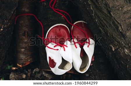 Leather baby vintage retro red and white boots with laces on wooden logs, first shoes