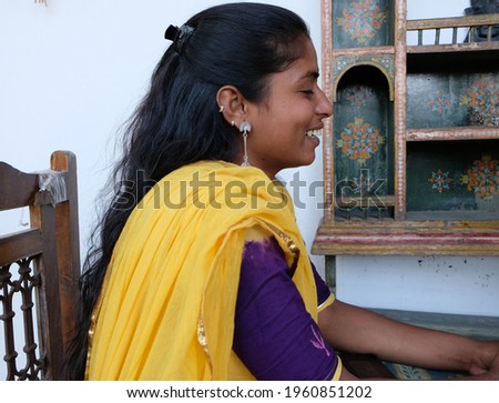 A profile portrait of a happy smiling Indian woman wearing a traditional sari dress sitting at the table
