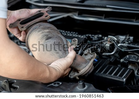 Close up Damaged Catalytic car in hand man remove from engine gasoline car dust clogged condition on filter in service concept Royalty-Free Stock Photo #1960851463