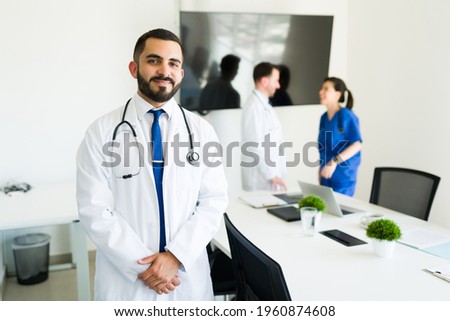 Happy to help his patients. Successful hispanic doctor and hospital director in a white coat getting ready to start a meeting with the medical board Royalty-Free Stock Photo #1960874608