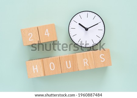 24 hours; Seven wooden blocks with "24 HOURS" text of concept and a clock.