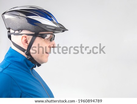Man cyclist in a bicycle helmet and transparent glasses on a light background