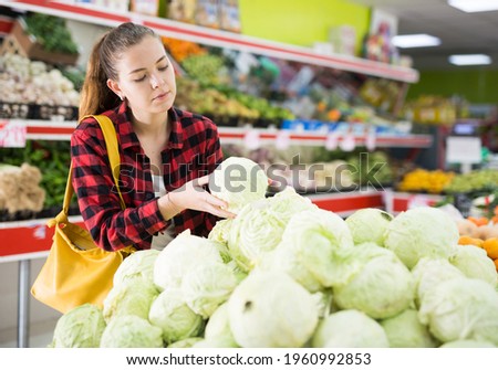 Positive european customer chooses cabbages at grocery store