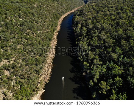 High angled aerial photo of boat travelling through the Nepean river on sunny autumn day. Visible recent flood water line running along river. 