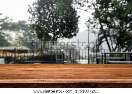 Empty wooden desk with blurred background of park or scenic look out.