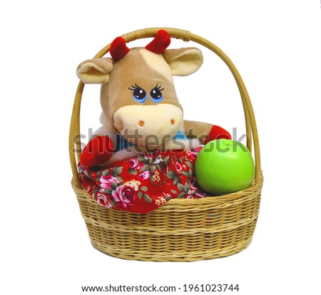 Plush cow. in the holiday basket. Apple. for table decoration, holiday. plush bull. new Year. Christmas. on an isolated white background.