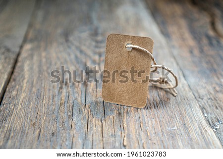 Cardboard price tag or blank tag for your label lying on the weathered wooden background. Copy space.